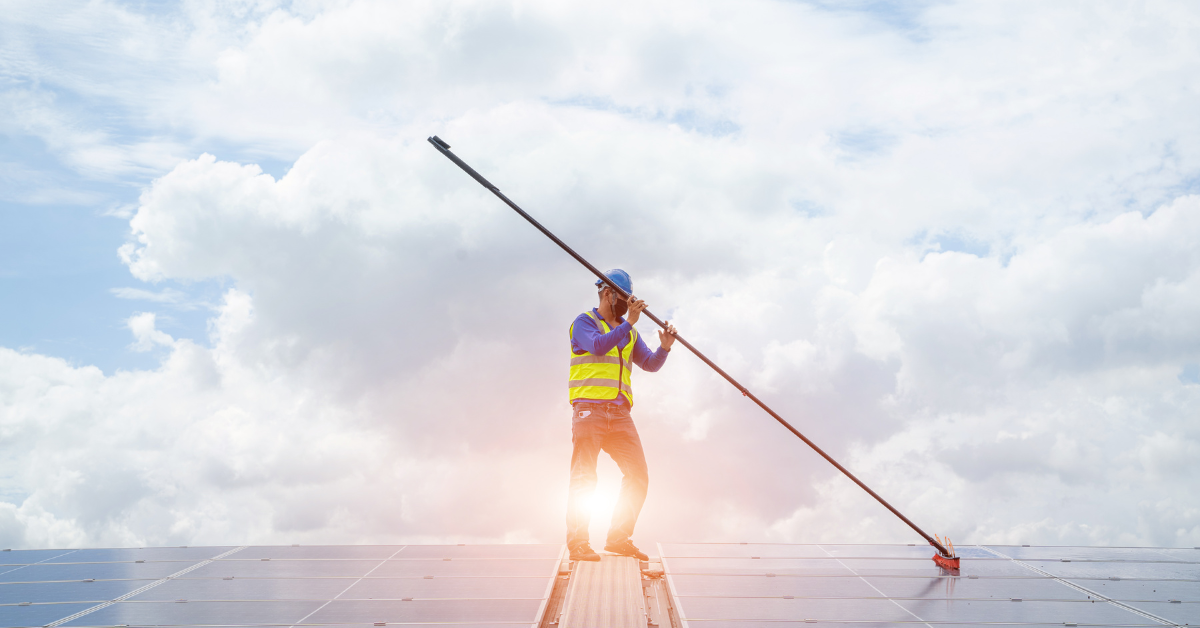 worker cleaning solar panels at dawn